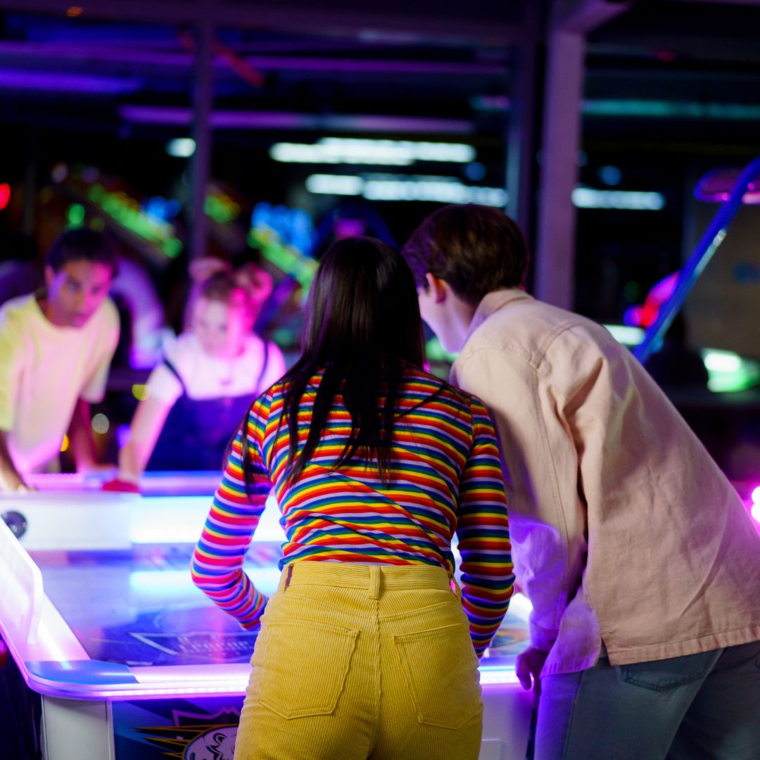 group playing air hockey game at arcade