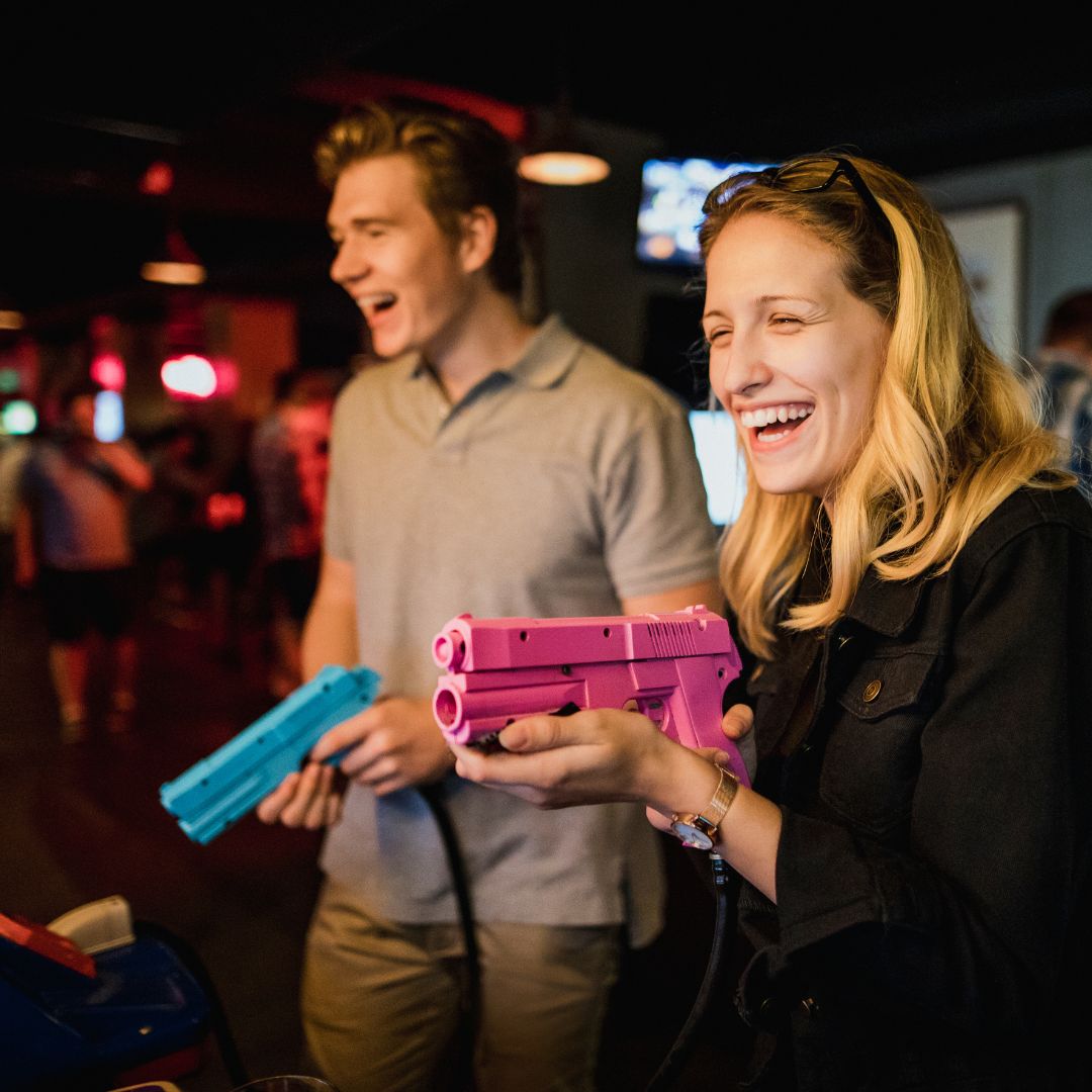 man and woman playing shooting game at arcade