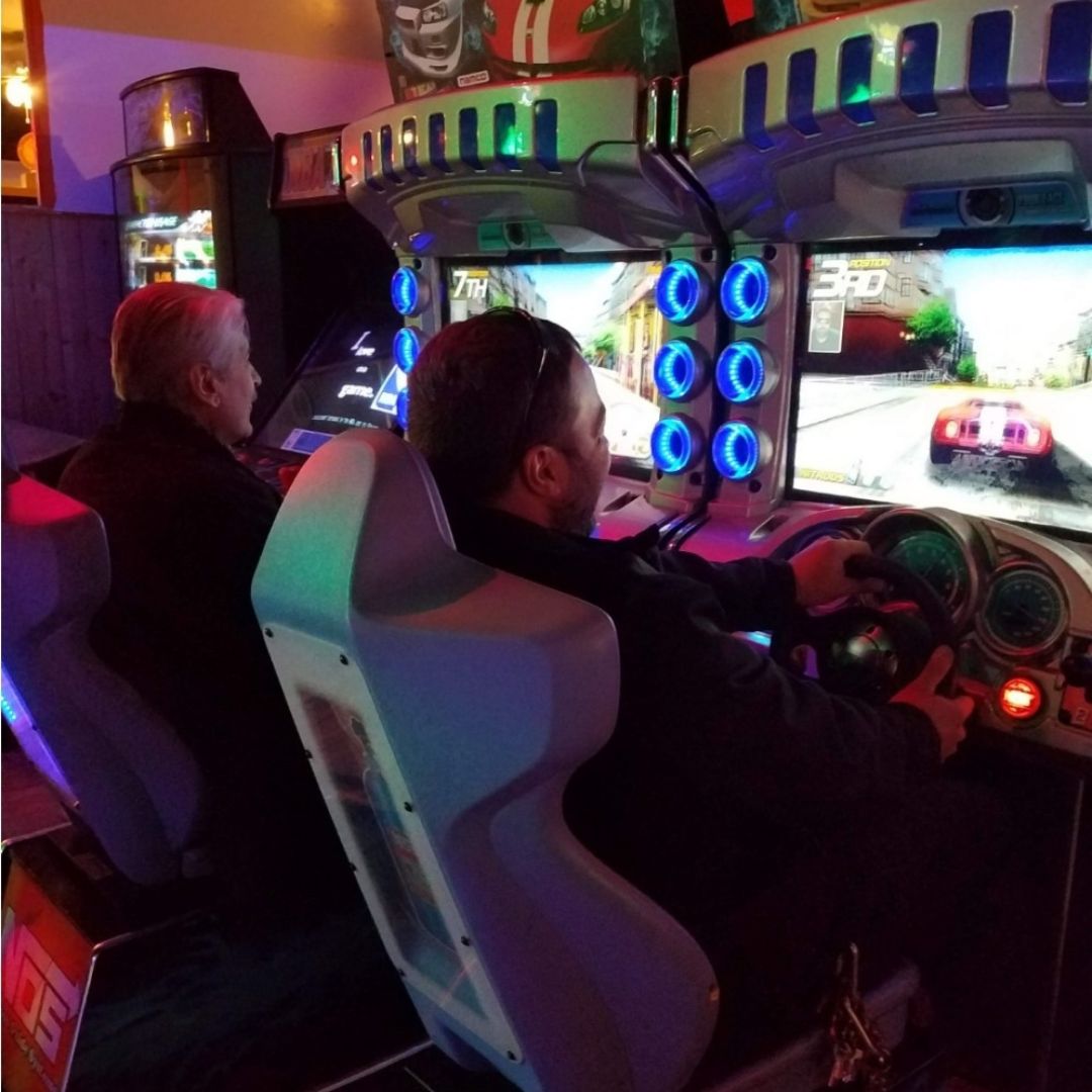 Two men playing arcade games. 