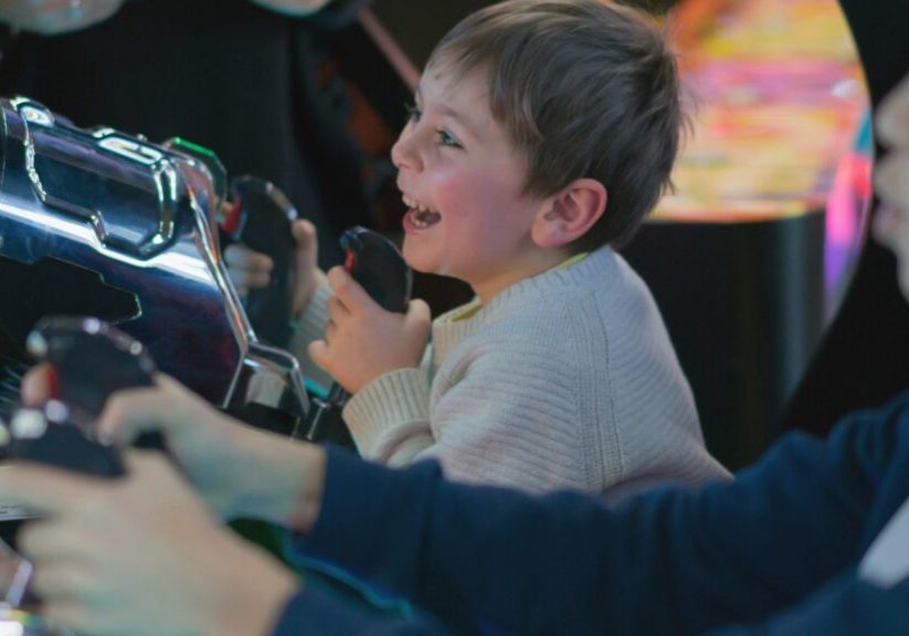 young child playing arcade shooting game